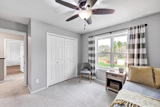 bedroom featuring light colored carpet, baseboards, a closet, and a ceiling fan