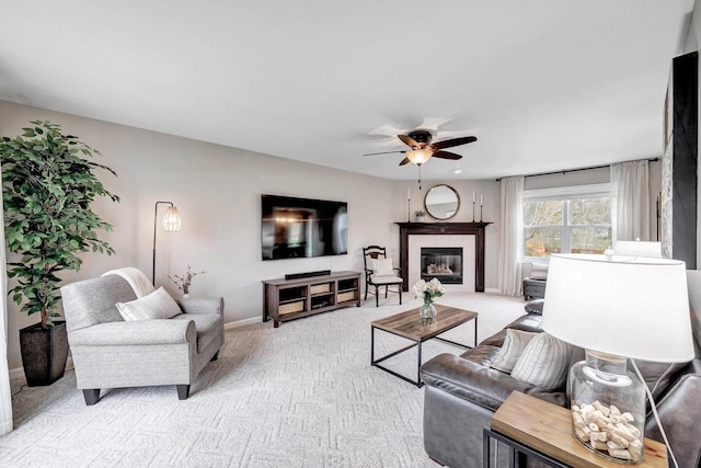 living room featuring ceiling fan, light carpet, baseboards, and a tile fireplace