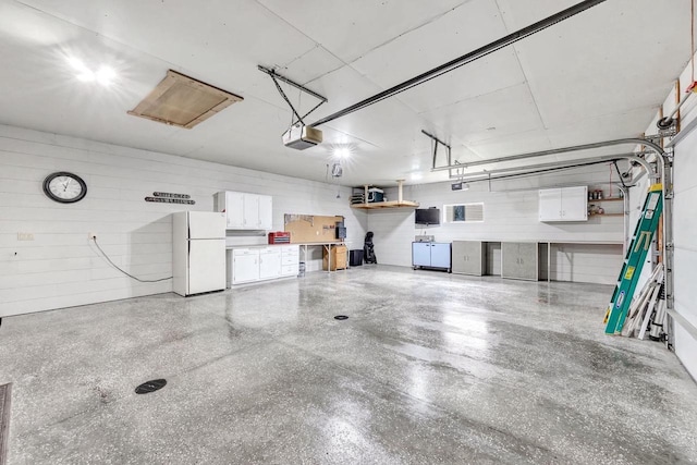 garage with freestanding refrigerator, a garage door opener, and washing machine and clothes dryer