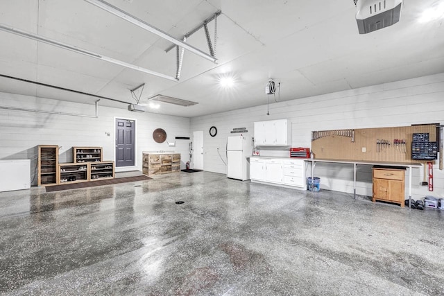 garage with freestanding refrigerator, a garage door opener, and a workshop area