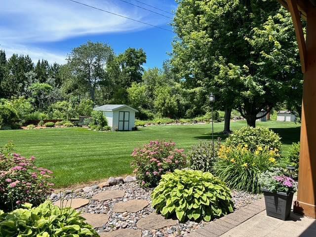 view of green lawn featuring a storage shed and an outbuilding