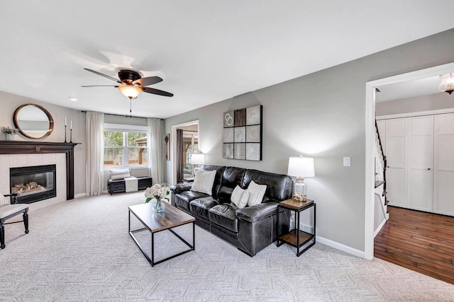 living area with ceiling fan, carpet flooring, baseboards, and a fireplace