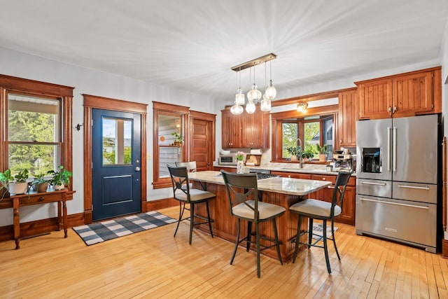1753 Oneida Ct, Grafton, WI 53024 - kitchen featuring high end refrigerator, a breakfast bar area, light wood finished floors, a center island, and a sink