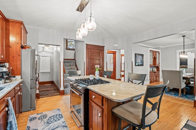 1753 Oneida Ct, Grafton, WI 53024 - kitchen featuring appliances with stainless steel finishes, light wood finished floors, light stone counters, a chandelier, and a kitchen breakfast bar