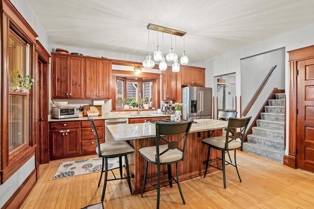 1753 Oneida Ct, Grafton, WI 53024 - kitchen with stainless steel appliances, a breakfast bar area, light wood finished floors, and light stone countertops