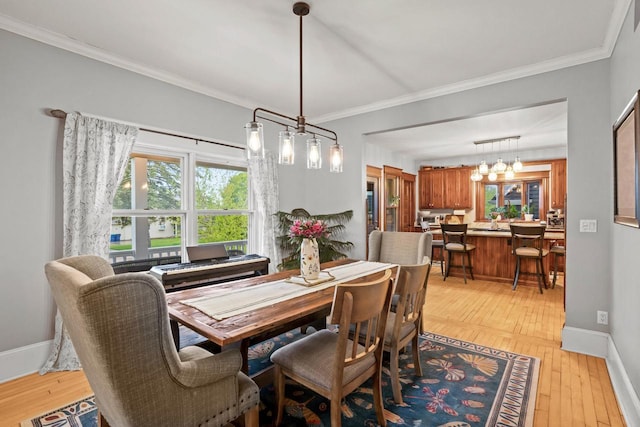 1753 Oneida Ct, Grafton, WI 53024 - dining area with light wood finished floors, crown molding, baseboards, and a chandelier