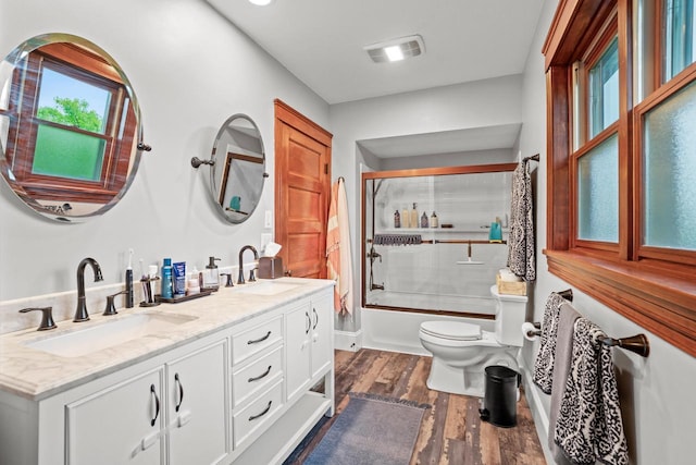 1753 Oneida Ct, Grafton, WI 53024 - bathroom with toilet, wood finished floors, double vanity, and shower / bath combination with glass door