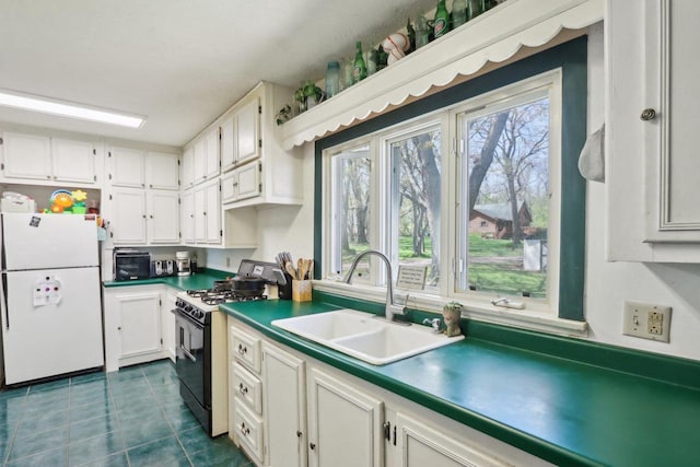 4121 1st Ave, Briggsville, WI 53920 - kitchen with freestanding refrigerator, range with gas stovetop, a sink, dark tile patterned flooring, and white cabinetry