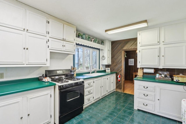 4121 1st Ave, Briggsville, WI 53920 - kitchen with range with gas cooktop, a sink, white cabinetry, wood walls, and dark tile patterned flooring
