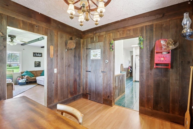 4121 1st Ave, Briggsville, WI 53920 - dining space featuring wooden walls, wood finished floors, a chandelier, and a textured ceiling