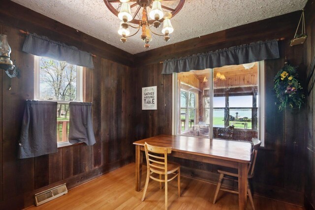 4121 1st Ave, Briggsville, WI 53920 - dining area with wood walls, a chandelier, wood finished floors, and a textured ceiling