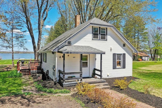 4121 1st Ave, Briggsville, WI 53920 - view of front facade featuring a front lawn, a chimney, a shingled roof, covered porch, and a deck with water view