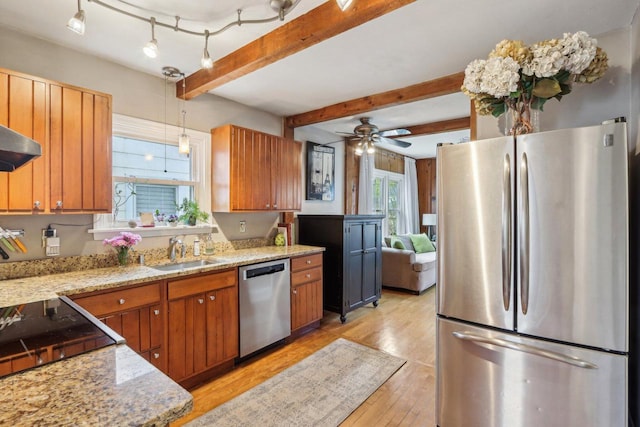 kitchen featuring stainless steel appliances, a sink, light wood-type flooring, beam ceiling, and brown cabinetry