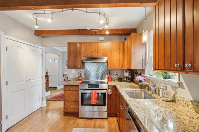 kitchen with appliances with stainless steel finishes, a sink, brown cabinetry, under cabinet range hood, and light wood-style flooring