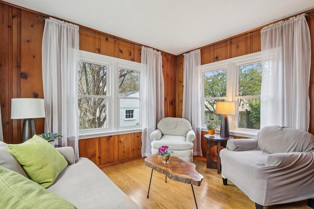 living area featuring light wood-style floors, wood walls, and baseboards