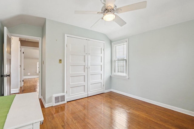 unfurnished bedroom featuring vaulted ceiling, light wood-type flooring, baseboards, a closet, and a ceiling fan