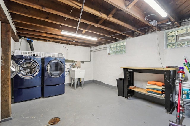 basement featuring washer and dryer, a sink, concrete block wall, and baseboards