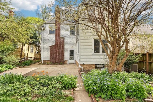 view of front of home with fence, a patio area, a chimney, and central AC unit