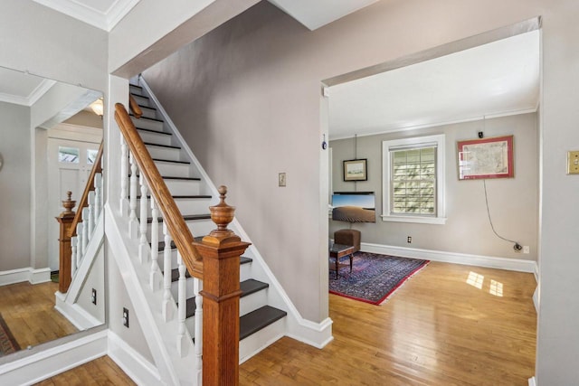 stairway featuring wood-type flooring, crown molding, and baseboards