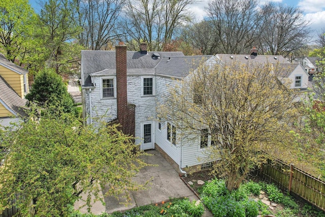 view of side of home with fence, a chimney, a patio area, and stone siding