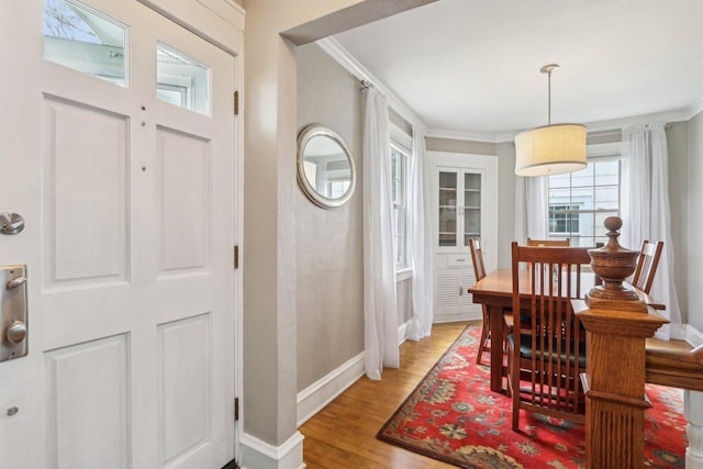 dining room featuring crown molding, light wood-type flooring, and baseboards