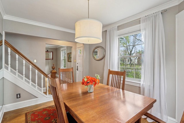 dining space with crown molding, wood finished floors, baseboards, and stairway