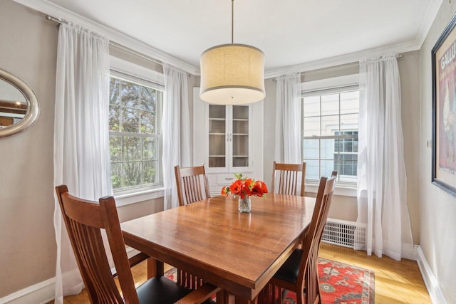 dining area featuring baseboards, light wood finished floors, and crown molding