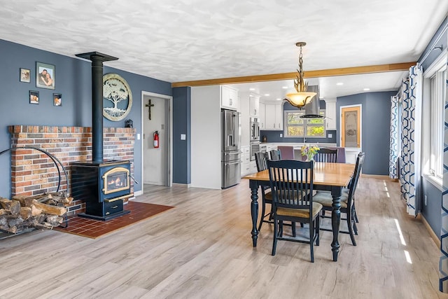 W3256 Princeton Rd, Green Lake, WI 54941 - dining space featuring a wood stove, light wood-style floors, and baseboards
