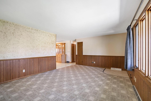 7704 Salisbury Rd, West Bend, WI 53090 - unfurnished room featuring a wainscoted wall, a baseboard radiator, and wood walls