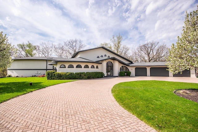 4455 Club Dr, Slinger, WI 53086 - view of front of house with curved driveway, a front lawn, a garage, and stucco siding
