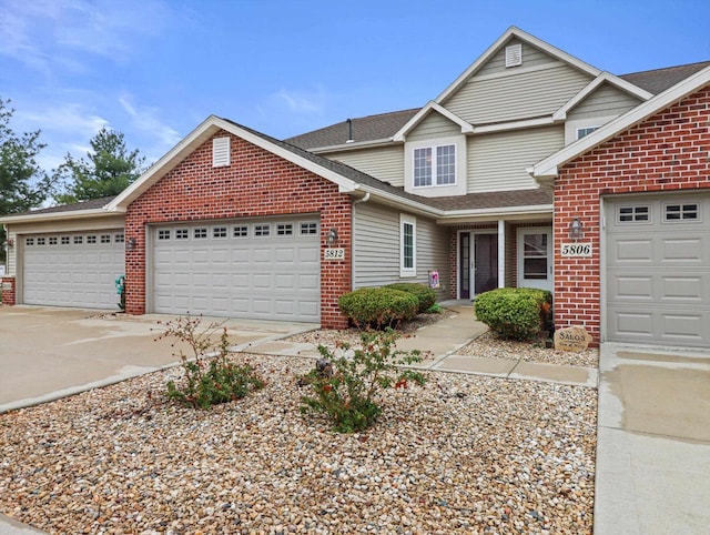 traditional-style house featuring brick siding, driveway, a garage, and a shingled roof