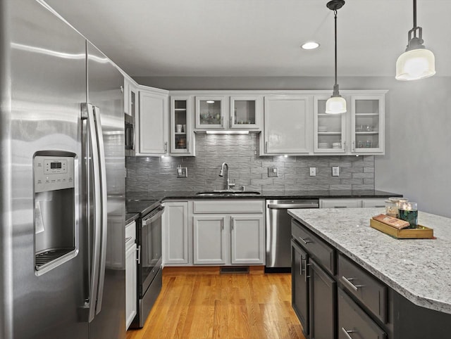 kitchen with appliances with stainless steel finishes, a sink, white cabinets, hanging light fixtures, and recessed lighting
