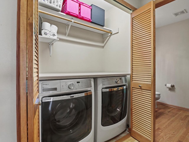 laundry area featuring washing machine and dryer and light wood finished floors