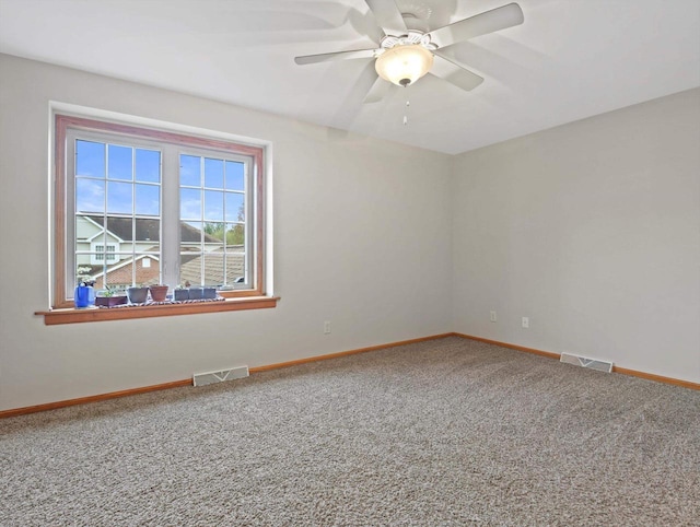 carpeted empty room featuring baseboards and a ceiling fan