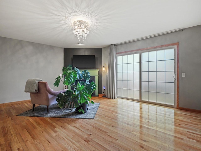 sitting room with wood finished floors, a chandelier, baseboards, and a fireplace