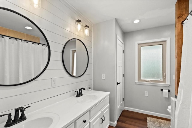 full bathroom featuring baseboards, wood finished floors, recessed lighting, double vanity, and toilet