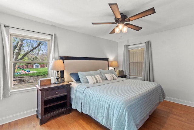 bedroom featuring baseboards, wood finished floors, and a ceiling fan