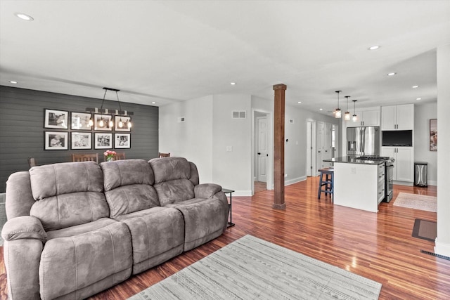 living area featuring recessed lighting, light wood-type flooring, baseboards, a chandelier, and decorative columns