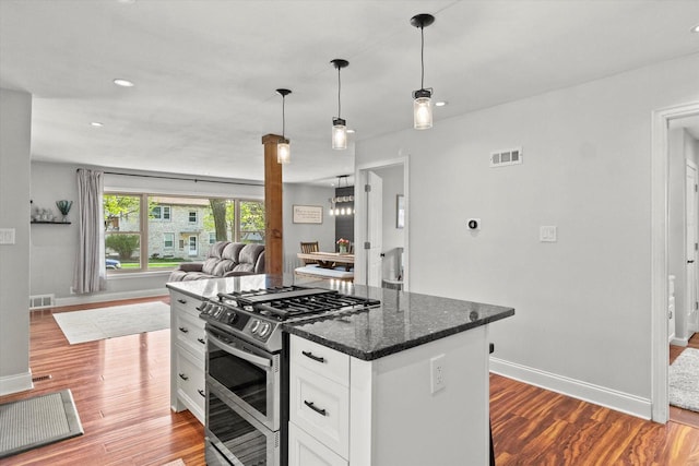 kitchen with range with two ovens, baseboards, wood finished floors, open floor plan, and white cabinets