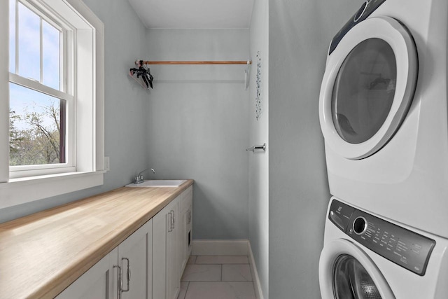 519 Park Ave, Little Chute, WI 54140 - laundry room with cabinet space, stacked washer / drying machine, baseboards, and light tile patterned floors