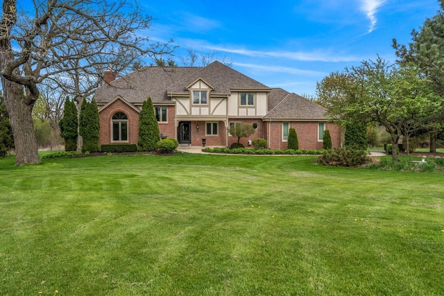 W343S9320 Jericho Dr, Eagle, WI 53119 - tudor home with brick siding, a chimney, a front yard, and a shingled roof