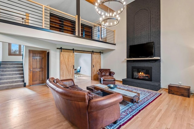 W343S9320 Jericho Dr, Eagle, WI 53119 - living room with a towering ceiling, a brick fireplace, wood finished floors, stairway, and a chandelier