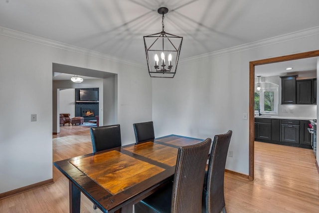W343S9320 Jericho Dr, Eagle, WI 53119 - dining space featuring light wood-style floors, a chandelier, baseboards, a warm lit fireplace, and ornamental molding