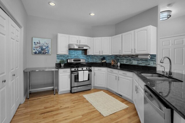 N53W16789 Prairie Dawn, Menomonee Falls, WI 53051 - kitchen featuring appliances with stainless steel finishes, a sink, under cabinet range hood, dark stone counters, and white cabinetry