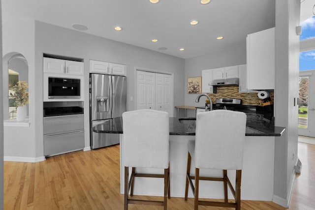 N53W16789 Prairie Dawn, Menomonee Falls, WI 53051 - kitchen featuring appliances with stainless steel finishes, a peninsula, under cabinet range hood, white cabinetry, and recessed lighting