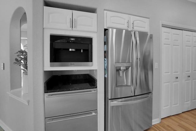N53W16789 Prairie Dawn, Menomonee Falls, WI 53051 - kitchen with stainless steel fridge, white cabinets, light wood-style flooring, arched walkways, and baseboards