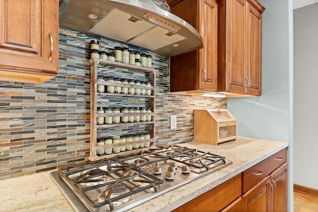 805 Mourning Dove Dr, Cottage Grove, WI 53527 - kitchen with wall chimney range hood, stainless steel gas cooktop, tasteful backsplash, brown cabinets, and light stone counters
