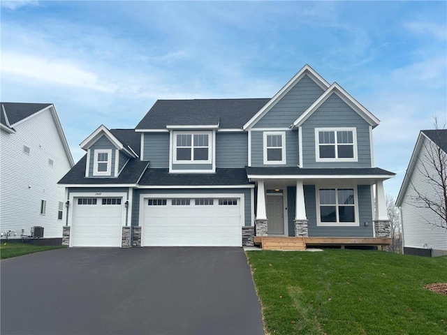 519 Lagrandeur Rd, Somerset, WI 54025 - craftsman-style home featuring stone siding, driveway, covered porch, a front yard, and a garage