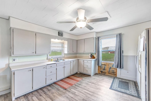 3265 County Road C, Oconto Falls, WI 54154 - kitchen featuring a sink, plenty of natural light, light wood-style flooring, ceiling fan, and a wainscoted wall