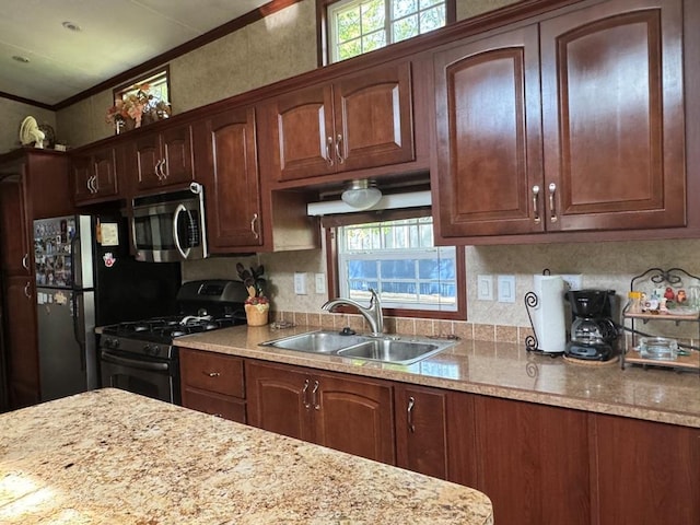 463 Aspen Way, Edgerton, WI 53534 - kitchen with appliances with stainless steel finishes, a sink, crown molding, decorative backsplash, and light stone counters